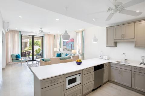 The image shows a bright and modern open-plan kitchen extending into a living area