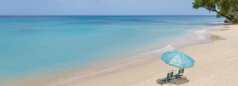 The image shows a serene beach scene with crystal clear turquoise blue waters and a fine sandy shore