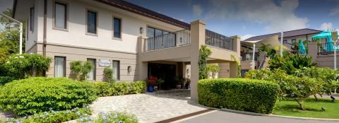 This image features a two-story building in a lush, landscaped setting