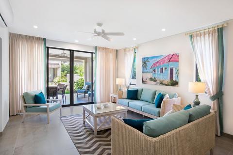 This image shows a modern and airy living room with a tropical coastal decor theme