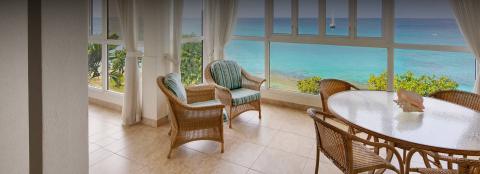 The image shows an elegantly furnished indoor space with an ocean view