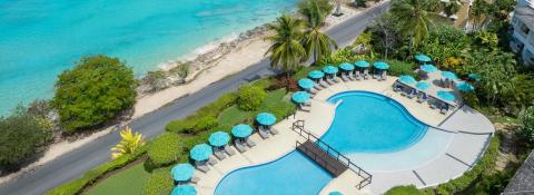 The image shows a picturesque view of a luxurious poolside area adjacent to a beach