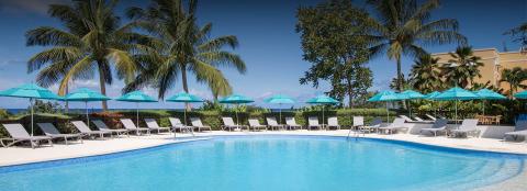 The image shows a tranquil outdoor resort pool area