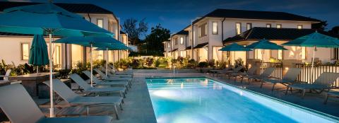 This image shows a serene evening setting at a luxurious pool area flanked by elegant residential buildings