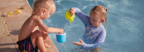 The image shows two young children playing by a swimming pool