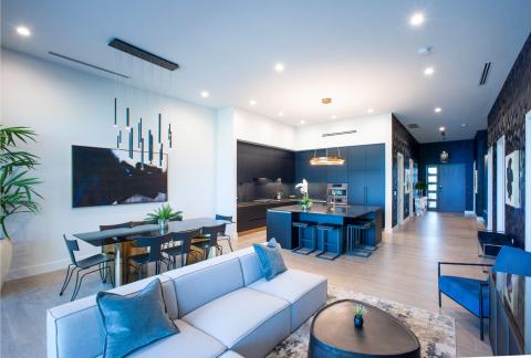 The image shows a modern and stylish interior of a residential space, featuring a combined living and dining area seamlessly transitioning into the kitchen