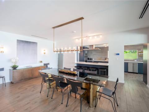 The image displays a modern, spacious kitchen and dining area featuring a minimalist design
