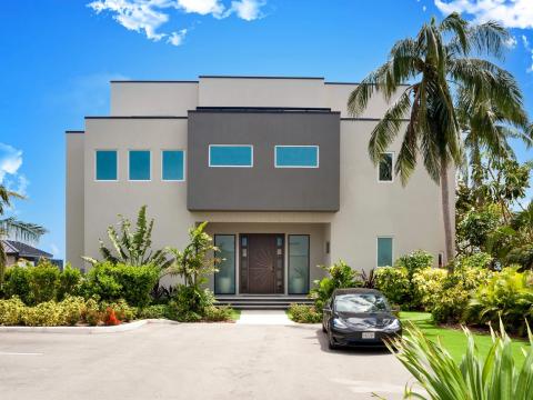 The image shows a modern house featuring a minimalist architecture style with cuboid shapes and flat surfaces
