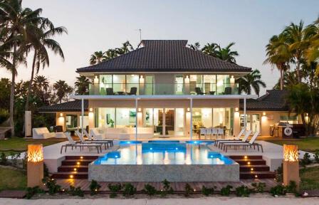 This image shows a luxurious two-story house with expansive glass windows
