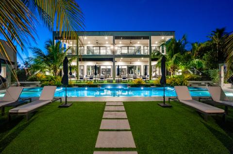 This image showcases a luxurious mansion at night, with a stunning outdoor setup