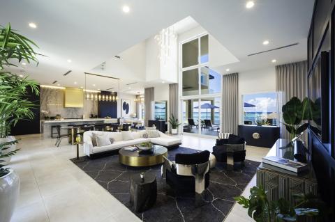 This image features a luxurious and modern interior space with a high-ceiling living room connected to an open kitchen area
