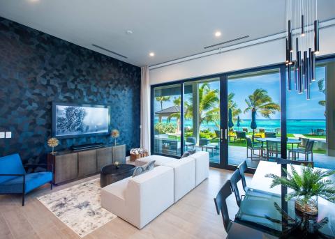 This image shows a modern, stylish living area with a view of a beachfront