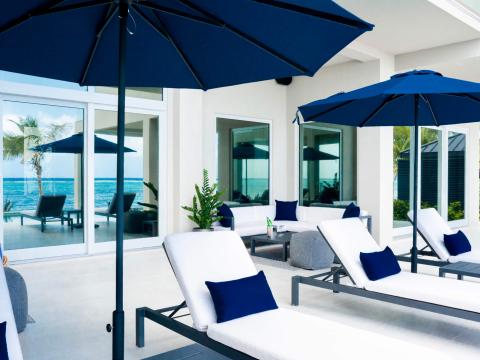 The image shows an elegant outdoor lounging area by the sea