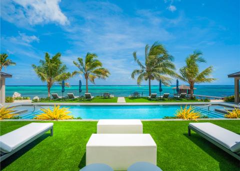 This image features a beautiful, luxurious poolside setting with a stunning ocean view