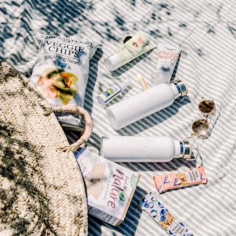 The image features a variety of items laid out on a striped blanket, suggesting a setting for a picnic or outdoor relaxation