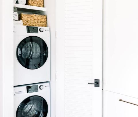 This image features a modern laundry room setup with a stacked washer and dryer