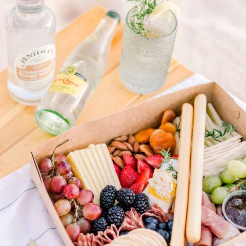 In the image, there is a picnic setup featuring a variety of food and drinks