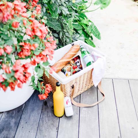 This image features a picnic setup with a wicker basket containing various items