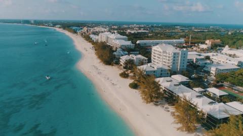This image shows an aerial view of a coastal area featuring a sandy beach along clear turquoise waters