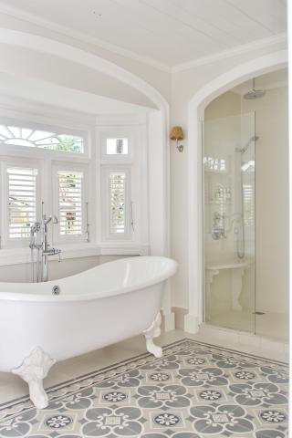 This image shows a bright and elegant bathroom featuring a standalone white bathtub with ornate clawfoot details