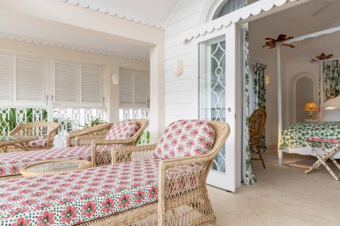 This image shows an elegantly decorated outdoor or porch area of a house with a cozy, tropical aesthetic