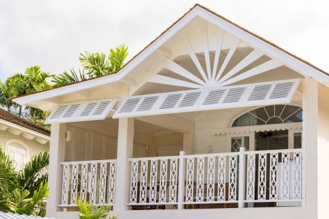 The image features a section of a house showing architectural details distinctive of tropical or Caribbean style
