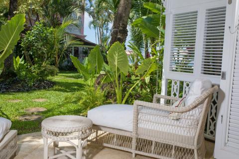 This image shows an inviting patio area in a lush, tropical garden setting