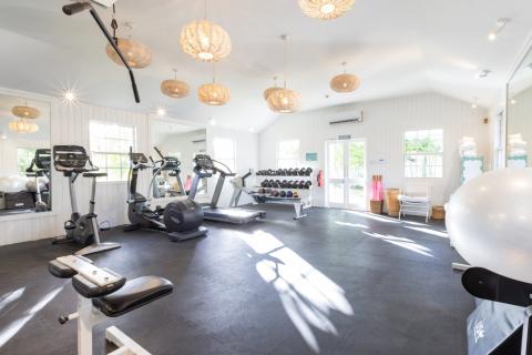 This image shows a bright and airy gymnasium, featuring a variety of exercise equipment