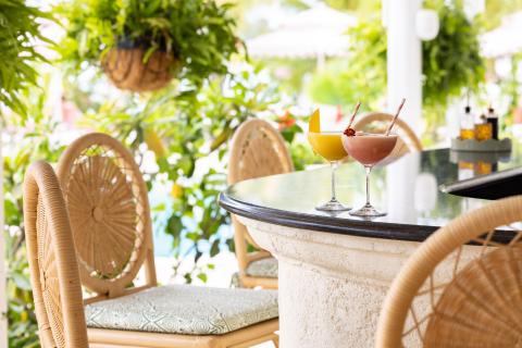 In the image, there are two cocktails placed on a round stone table at an outdoor seating area