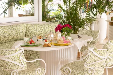 The image features an elegant and cozy breakfast setting in a bright and well-decorated indoor area with natural light streaming in through the windows