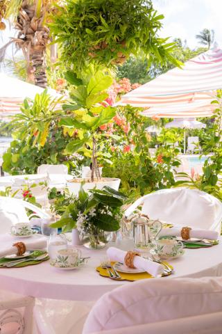 This image features a beautifully arranged outdoor dining setting in a lush garden environment