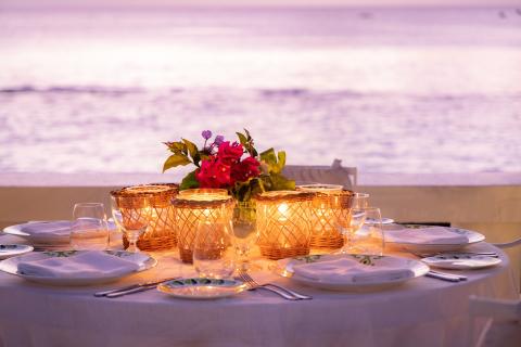 This image shows a beautifully set dinner table for an outdoor meal, likely at a seaside location