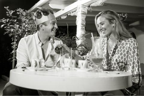 The image features a man and a woman enjoying a festive dinner setting outdoors