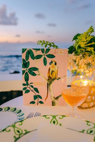 This image features an outdoor dining setting at twilight with a view of the sea