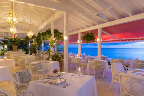 This image shows an elegant outdoor dining area at a restaurant by the sea
