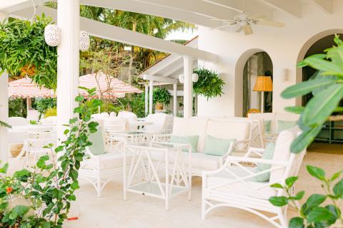 This image depicts a sophisticated and airy outdoor seating area, likely at a resort or in a tropical location