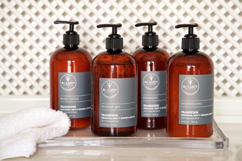 The image displays a set of four amber-colored bottles, each equipped with black pump dispensers