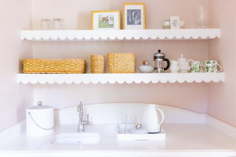 This image shows a neatly arranged kitchenette or drink preparation area with a light color scheme