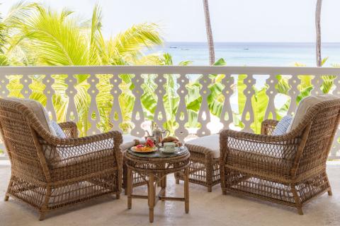This image shows a peaceful balcony setup overlooking a tropical beach