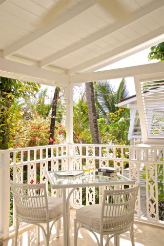 This image features a beautifully appointed balcony or porch area with a tropical scenic view