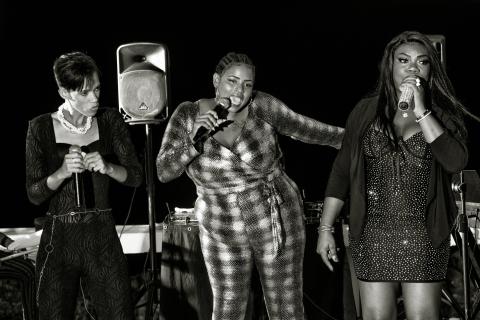 This black and white image features three women performing on a stage