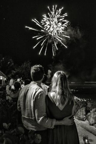 This image captures a couple from behind, embracing as they watch fireworks exploding in the sky
