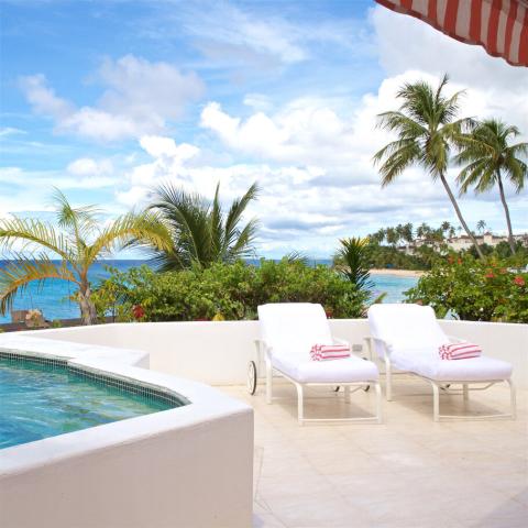 This image depicts a luxurious outdoor relaxation area overlooking a scenic beachfront view