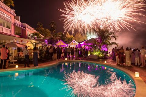 This image shows an outdoor evening event at a luxurious location featuring a swimming pool