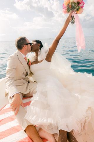 This image features a joyful wedding moment with a couple kissing on a boat