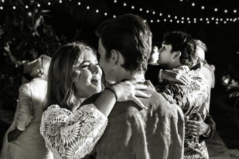 This black-and-white image captures a romantic and joyful scene at what appears to be an evening outdoor event, possibly a wedding reception or party