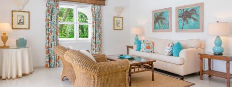 The image depicts an elegantly appointed living room with a tropical decor theme