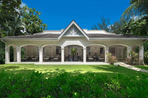 This image features a beautiful, single-story house surrounded by a lush garden