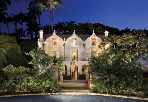 This image features a large and elegant house taken at twilight, showcasing its illuminated windows and architectural details