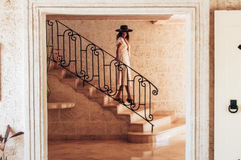 This image shows an elegant interior scene featuring a woman standing on a staircase